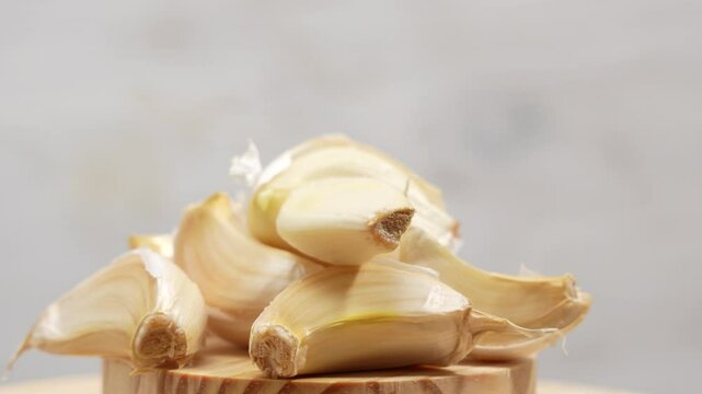 A pile of garlic cloves on a wooden cutting board
