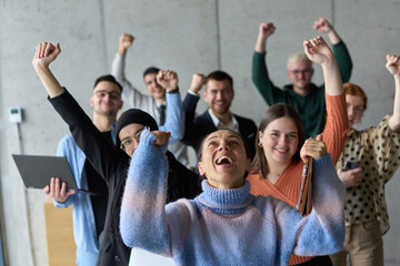 A diverse team of business professionals ecstatically celebrating their success in a modern office,...