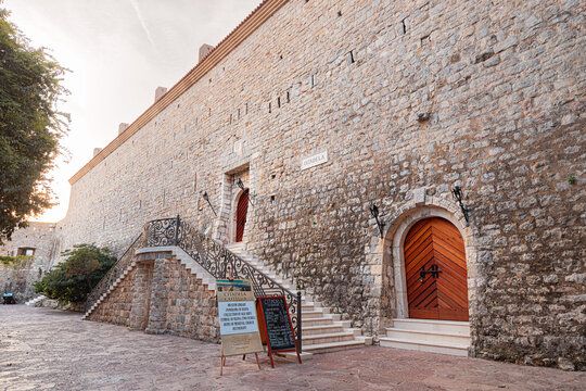24 October 2024, Budva, Montenegro: Ornate wrought iron railing adorns white staircase leading to entrance of historic stone fortress Citadela