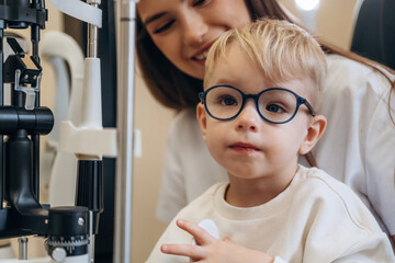 By the modern device. Little boy is having check up in the ophthalmologist cabinet