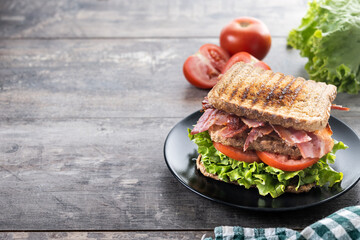 Bacon sandwich with lettuce and tomato on wooden table. Copy space