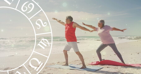 Image of horoscope over happy senior biracial couple practicing yoga at beach