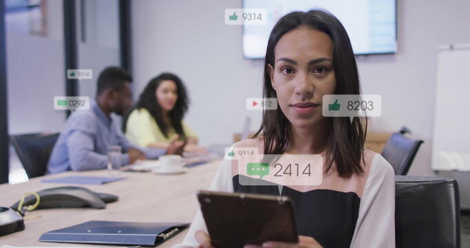 Image of icons and numbers over biracial businesswoman in office