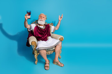 Full body portrait historical character costume man sit throne hold wine glass empty space of...