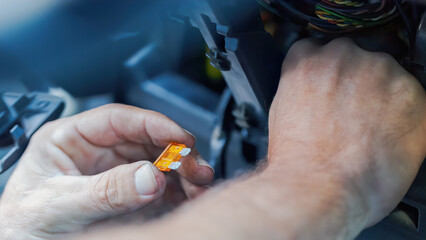 A technician's hand carefully replaces a car fuse inside the vehicle dashboard, emphasizing precision and attention to detail. Automotive repair, showcasing expertise in electrical system maintenance