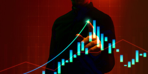 Conceptual image of businessman pointing at rising data trends, candlestick charts on digital interface, symbolizing growth and success. Concept of business, analytics, technology, financial industry