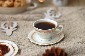 Various Christmas decorations, lit candles, cup of tea or coffee, cookies, books, presents and soft blanket on the table. Holiday hygge at home. Selective focus.