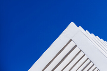 The fence on the sky background against the wall And abstract architecture contrasting with the blue sky With clear and beautiful light shadows Modern