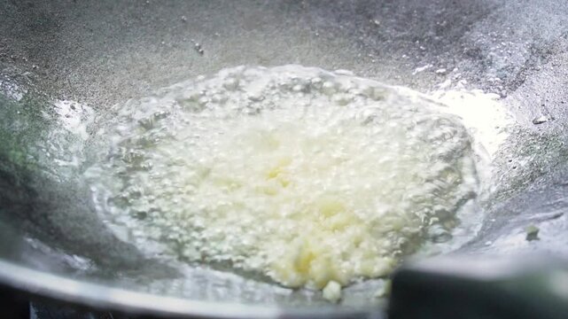 Finely chopped garlic being fried in a hot pan. Slow motion footage of cooking in the kitchen. Garlic is an ingredient in cooking. A pungent vegetable with health benefits. Cooking by frying