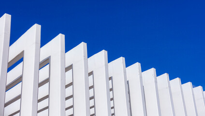 The fence on the sky background against the wall And abstract architecture contrasting with the blue sky With clear and beautiful light shadows Modern