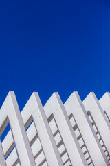 The fence on the sky background against the wall And abstract architecture contrasting with the blue sky With clear and beautiful light shadows Modern