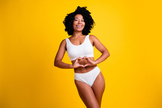 No filter studio photo of slender woman underwear showing arms heart enjoying self acceptance isolated yellow color background