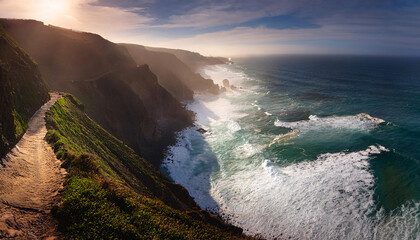 Obraz premium Dramatic coastal cliffs meet turquoise waves under a cloud-strewn sky at sunset