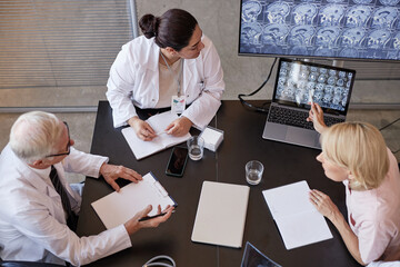 High angle shot of Middle Eastern female radiologist sitting at meeting table, while colleague...