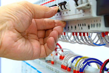 The hand holds the automatic current switch in the electrical switchboard. Close-up. Soft focus.