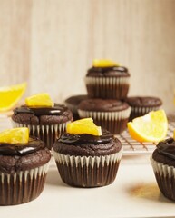 Homemade gluten free chocolate orange cupcakes topped with chocolate frosting and sliced orange. Close up. Selective focus.