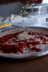 A close-up of grated cheese being added to a pizza highlights the perfection in preparation.