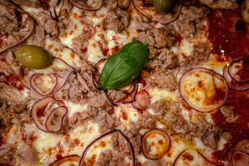 A close-up of a fully baked pizza topped with various ingredients, including olives, onions, and basil.