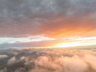 Drone view of clouds at sunset. Beautiful clouds covered the city. Bright evening golden, pink and...