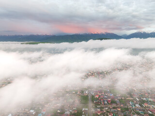 Drone view of the town and mountains at sunset. Beautiful clouds covered the city. Bright evening...