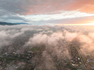 Drone view of the town and mountains at sunset. Beautiful clouds covered the city. Bright evening...