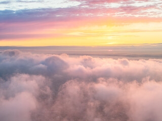 Naklejka premium Drone view of clouds at sunset. Beautiful clouds covered the city. Bright evening golden, pink and blue landscape.