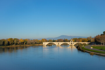 Saint-B&eacute;n&eacute;zet Bridge (Pont d'Avignon) is a medieval bridge to the Rh&ocirc;ne River, a well-known city symbol. Autumn, clear sunny day. Prealps on the horizon. Copy space. 
