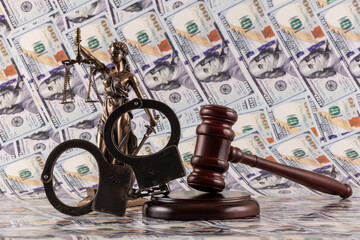 Handcuffs and a judge's gavel against a background of $100 bills