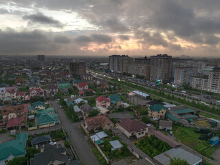 Obraz premium Drone view of the town and mountains at sunset. Beautiful clouds covered the city. Golden sunset. Evening landscape.