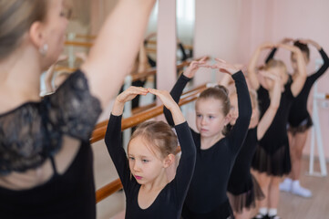 Children's ballet school. Caucasian woman teaching ballet to little girls. 