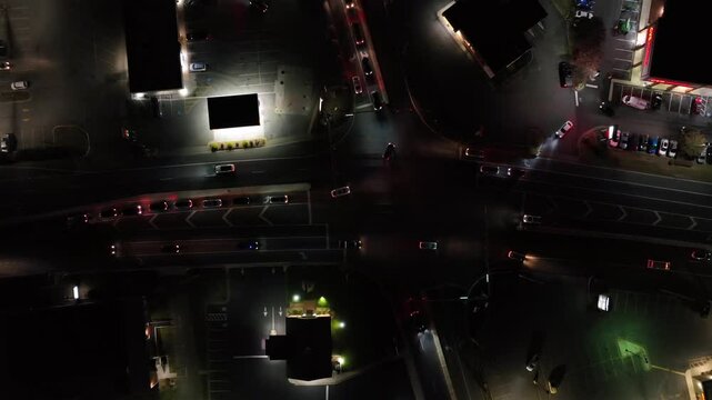 Driving cars on junction at night. American suburb area with gas station, restaurant and cvs pharmacy. Aerial top down. United states, Virginia.