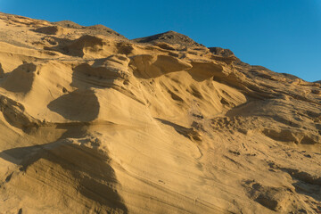A wide shot of La Pared beach on the island of Fuerteventura, Canary Islands, Spain. The photo showcases the beautiful blue sky, the turquoise ocean with gentle waves, and the sandy beach with seaweed
