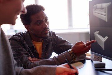 African American man engaging in collaborative design process with colleague, using computer equipment in modern workspace environment enhancing creative productivity
