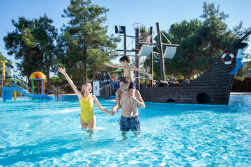 A joyful family having fun together at an aquapark, enjoying water slides, pools, and lively summer vibes.