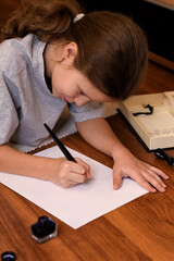 girl lying on the floor, in front of her is a sheet of paper, pen and ink