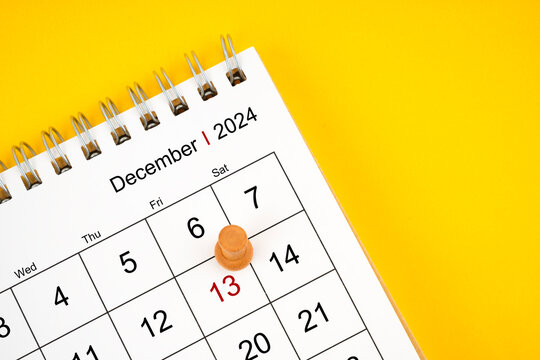 December 2024 desk calendar and wooden push pin on 13 Friday.