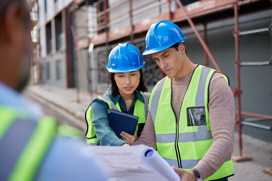 Construction workers discussing blueprint at building site
