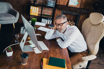 Photo of tired nice man specialist dressed white shirt working modern gadget indoors workstation...