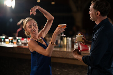 A happy couple spending time together at a stylish bar, sipping drinks and enjoying the lively and...