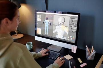 Individual working on 3D modeling software on desktop, creating skeletal structure. Various office...