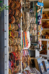 Friendship bracelets, bead necklaces and gift stall. Rows of brightly coloured trinkets for sale. Tourist market.