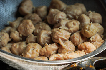 Obraz premium A close-up shot of numerous brown meatballs in a metal colander. The image focuses on the texture and color of the food. Close-up of Brown Meatballs in a Colander