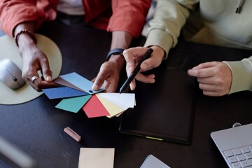 Two individuals collaborating and discussing color scheme by examining a color palette together....
