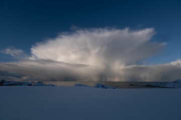 Obraz premium Dramatic Cloud Formation Over Snowy Landscape