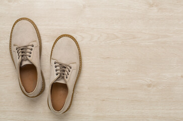 Beige suede shoes on wooden background, top view