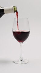Wine bottle pouring into white-background wine glass isolated