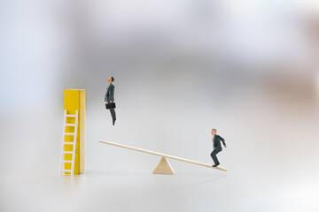 Fototapeta premium Workplace inequality, power dynamics, competition, and short cut to career growth : Miniatures figures, along with the seesaw and a ladder, highlight an imbalance or differing level of opportunity.