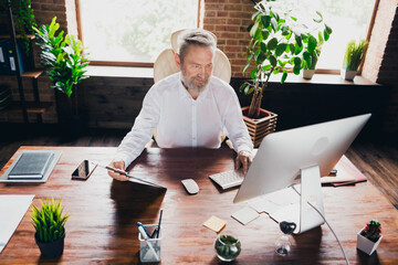 Photo of handsome man entrepreneur dressed shirt reading document report contract indoors...