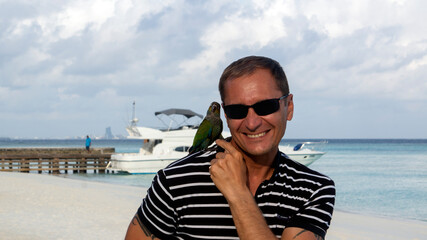 Photo shoot of a young man on the beach with a parrot. 