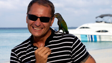 Photo shoot of a young man on the beach with a parrot. 